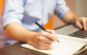 Mann macht Notizen und nutzt Kreditrechner auf Laptop