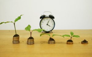 Fünf Münzstapel für Kredit umschulden mit Uhr im Hintergrund