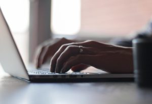 Person schreibt an Laptop Kredit umschulden