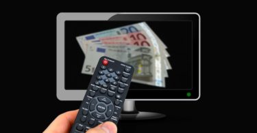 Geld für Rundfunkbeitrag auf Bildschirm und Hand die Fernbedienung hält