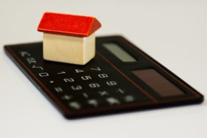 Miniaturhaus auf Taschenrechner für Berechnung Vorfälligkeitsentschädigung