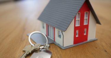 Miniaturhaus und Schlüssel symbolisch für Plan auf Erbbaugrundstück zu bauen