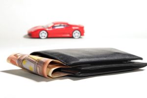 Rotes Spielzeugauto hinter 50-Euro-Scheinen in Geldbeutel für Autokredit