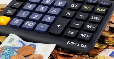 Taschenrechner und Geld um Höhe der Versicherungssteuer zu berechnen