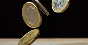 Fallende Euromünzen vor schwarzem Hintergrund für Kreditvergleich