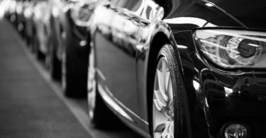 Hintereinander parkende schwarze Autos mit Kfz Versicherung